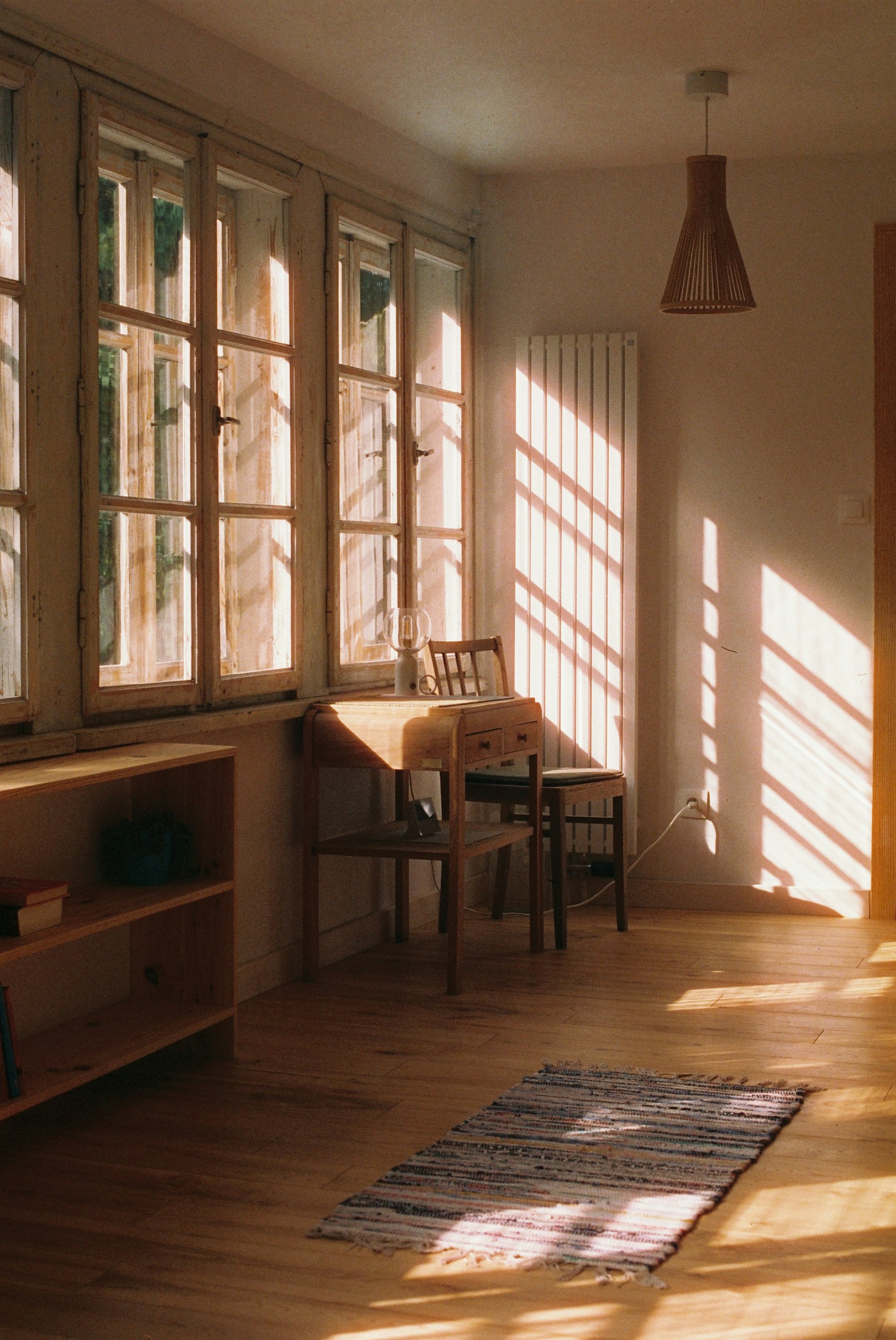 Pièce ensoleillée avec parquet, mobilier et fenêtres en bois. Photographie d’ambiance indépendante de Menuiserie Faron.